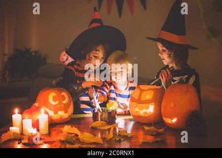 Bambini, fratelli ragazzi, giocando con zucca scolpita a casa su Halloween, facendo pozione magica Foto Stock