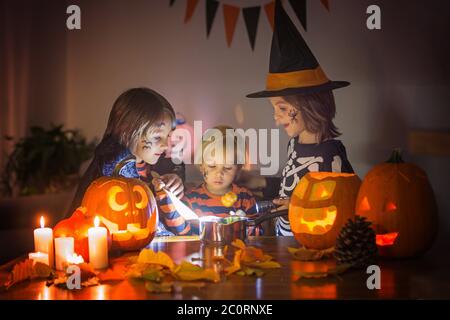 Bambini, fratelli ragazzi, giocando con zucca scolpita a casa su Halloween, facendo pozione magica Foto Stock