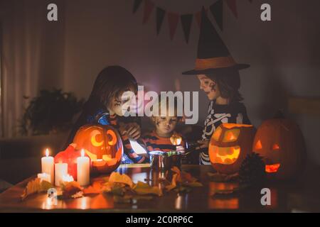 Bambini, fratelli ragazzi, giocando con zucca scolpita a casa su Halloween, facendo pozione magica Foto Stock