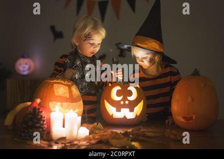 Adorabili bambini, bimbo e bambina, giocando con la zucca intagliata di Halloween e la decorazione a casa Foto Stock