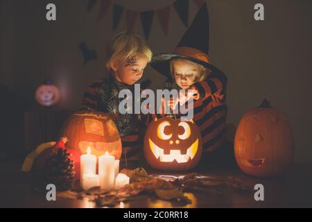 Adorabili bambini, bimbo e bambina, giocando con la zucca intagliata di Halloween e la decorazione a casa Foto Stock