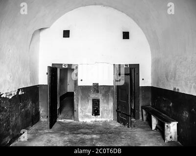 Due vecchie celle di prigione con porta di legno. Vista dal corridoio. Immagine in bianco e nero. Foto Stock