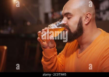 Primo piano di un uomo bearded che si gode bere una deliziosa birra fresca al pub, spazio di copia Foto Stock