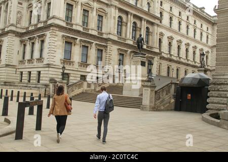 Una passeggiata di coppia verso la statua di Clive. Robert Clive, il primo barone Clive meglio sapere come Clive dell'India, che ha stabilito il dominio britannico in India si trova fuori dal Ministero degli Esteri. Clive è stato il primo governatore della Presidenza del Bengala sotto la Compagnia dell'India orientale. Le autorità hanno imbarcato monumenti e statue a Londra soprattutto a causa del loro legame passato alla schiavitù in previsione del possibile vandalismo con organizzazioni di estrema destra e dimostrazione di materia di Black Lives in programma per questo fine settimana. Foto Stock