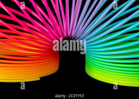 Rivestimento in plastica slinky multicolore isolato su sfondo nero Foto Stock