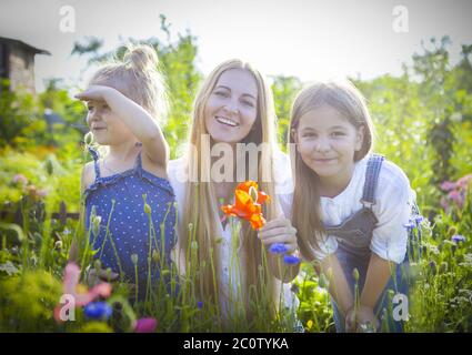 Donna felice e le sue figlie nel giardino fiorente di primavera Foto Stock