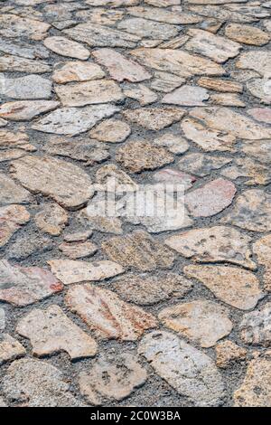 La strada pavimentata da pietre selvagge di varie forme. Pavimento in pietra selvaggia. Ripetizione di forme irregolari Foto Stock