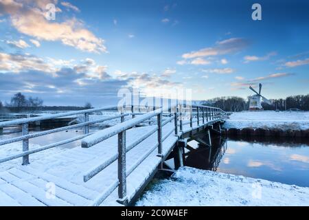 Ponte via fiume al mulino a vento in inverno Foto Stock