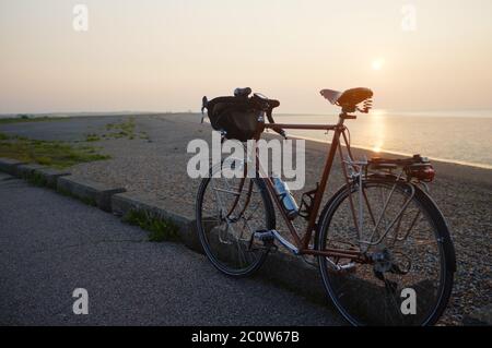 Cavalcare al tramonto su una classica bicicletta da corsa. Foto Stock