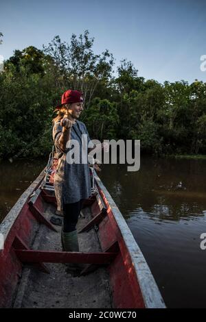 donna bionda che pesca su una canoa nel fiume Foto Stock