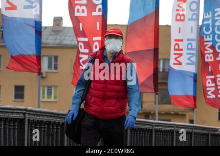 Mosca, Russia. 12 giugno 2020 UN uomo che indossa una maschera protettiva e guanti cammina sul ponte Krymsky decorato con striscioni con messaggi che leggono 'Siamo Russia, ci stiamo insieme' durante una festa nazionale conosciuta come la Russia Day, celebrata il 12 giugno, in mezzo alla pandemia del romanzo coronavirus COVID-19 malattia Foto Stock