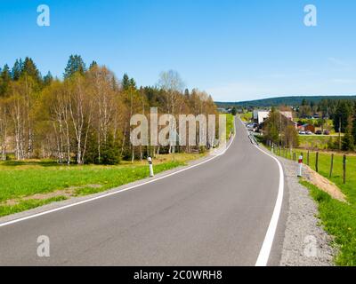 Stretta strada rurale asfaltata nel paese in piena soleggiata giornata estiva Foto Stock