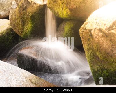 Vista dettagliata di una piccola cascata di fiume su un fiume di montagna rocciosa. Acqua di seta sfocata da un colpo di esposizione lungo. Foto Stock