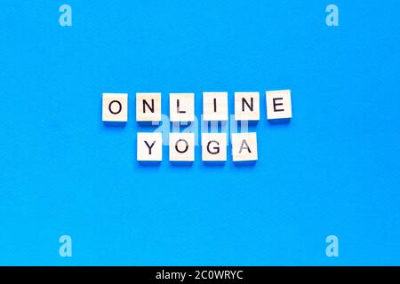 La parola ONLINE YOGA scritta in legno tipo letterpress su sfondo blu. Vista dall'alto. Layout piatto. Foto Stock