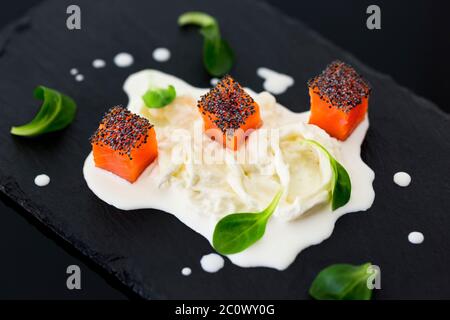 Noci di salmone con semi di papavero su stracciatella e foglie valeriane Foto Stock