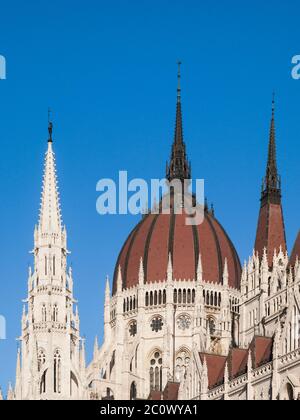 Vista dettagliata dell'edificio storico del Parlamento ungherese, noto anche come Orszaghaz, con tipica cupola centrale su un cielo blu chiaro. Budapest, Ungheria, Europa. E' un notevole punto di riferimento e sede dell'Assemblea Nazionale dell'Ungheria. Sito patrimonio dell'umanità dell'UNESCO. Foto Stock