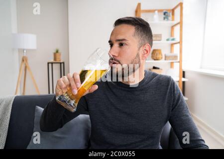 Uomo bere birra da solo a casa Foto Stock