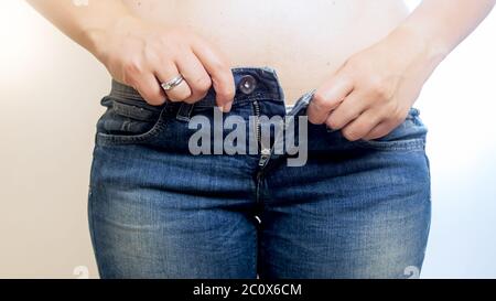 Giovane donna che cerca di buttare jeans stretti Foto Stock