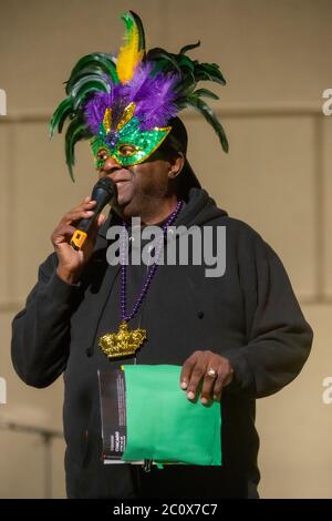 Indossando una maschera di piuma, un maestro afroamericano delle cerimonie presiede ad un'osservanza jazz di Mardi Gras a Costa Mesa, CA. Foto Stock