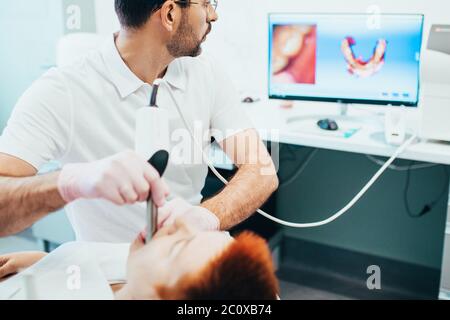 Il dentista esegue la scansione della ganascia e crea un modello 3D sul computer per la produzione di una protesi dentaria Foto Stock