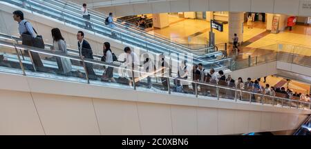 I passeggeri che cavalcano la scala mobile all'Aeroporto Internazionale Haneda di Tokyo, Giappone Foto Stock