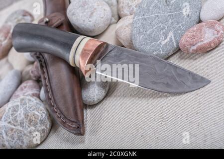 Coltello da lavoro e una custodia in pelle su sfondo in pietra Foto Stock