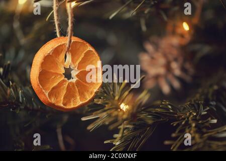 Zero rifiuti natale concetto. Albero di Natale decorato con ornamenti fatti di materiali naturali - fette di arancio secco e coni. Foto Stock