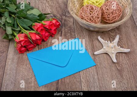 Busta blu, rose rosse e stelle marine su uno sfondo di legno Foto Stock