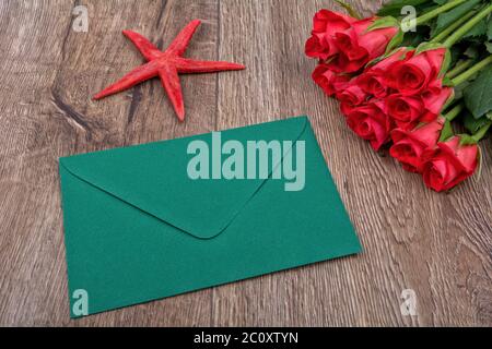 Busta verde, rose rosse e stelle marine su uno sfondo di legno Foto Stock