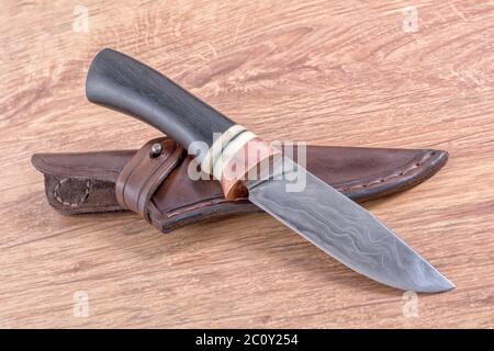 Coltello da lavoro e una custodia in pelle su sfondo di legno Foto Stock