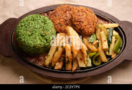 SIZZLER VEGETALE CON PATATINE FRITTE, PATATINE DI FAGIOLI, RISO SPINACI, ZUCINI, CAPSICUM, POMODORI CILIEGINI, CAVOLO, CIPOLLE E SALSA DI FAGIOLI NERI Foto Stock