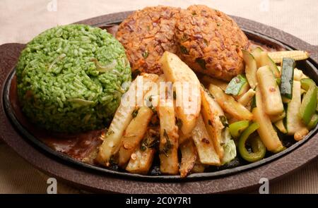SIZZLER VEGETALE CON PATATINE FRITTE, PATATINE DI FAGIOLI, RISO SPINACI, ZUCINI, CAPSICUM, POMODORI CILIEGINI, CAVOLO, CIPOLLE E SALSA DI FAGIOLI NERI Foto Stock