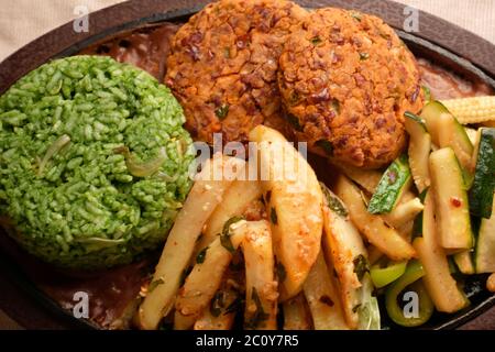 SIZZLER VEGETALE CON PATATINE FRITTE, PATATINE DI FAGIOLI, RISO SPINACI, ZUCINI, CAPSICUM, POMODORI CILIEGINI, CAVOLO, CIPOLLE E SALSA DI FAGIOLI NERI Foto Stock