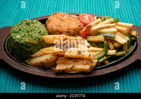 SIZZLER VEGETALE CON PATATINE FRITTE, PATATINE DI FAGIOLI, RISO SPINACI, ZUCINI, CAPSICUM, POMODORI CILIEGINI, CAVOLO, CIPOLLE E SALSA DI FAGIOLI NERI Foto Stock