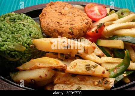 SIZZLER VEGETALE CON PATATINE FRITTE, PATATINE DI FAGIOLI, RISO SPINACI, ZUCINI, CAPSICUM, POMODORI CILIEGINI, CAVOLO, CIPOLLE E SALSA DI FAGIOLI NERI Foto Stock