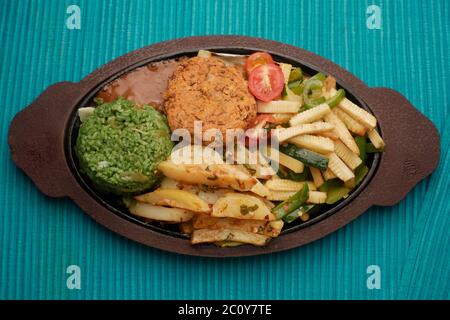 SIZZLER VEGETALE CON PATATINE FRITTE, PATATINE DI FAGIOLI, RISO SPINACI, ZUCINI, CAPSICUM, POMODORI CILIEGINI, CAVOLO, CIPOLLE E SALSA DI FAGIOLI NERI Foto Stock