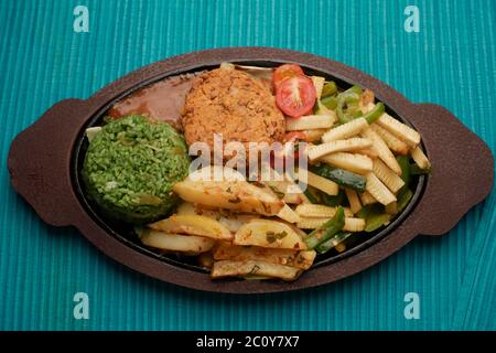 SIZZLER VEGETALE CON PATATINE FRITTE, PATATINE DI FAGIOLI, RISO SPINACI, ZUCINI, CAPSICUM, POMODORI CILIEGINI, CAVOLO, CIPOLLE E SALSA DI FAGIOLI NERI Foto Stock