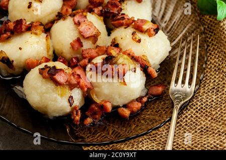 Gli gnocchi di patate ripiene di carne serviti con pancetta affumicata su una piastra Foto Stock