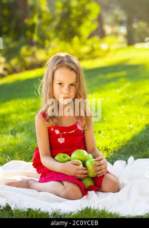 Funny bambina con mele verdi in estate park Foto Stock