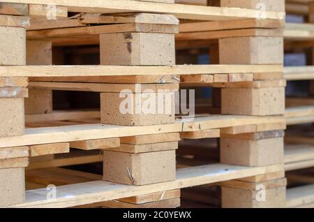 Una pila di nuovi pallet in legno. Pallet vuoti in un deposito all'aperto. Logistica e confezionamento. Messa a fuoco selettiva. Foto Stock