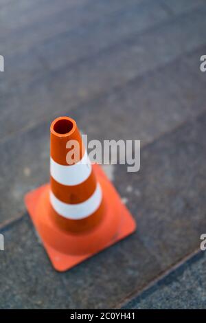 Cono di traffico, con bianco e strisce arancioni su grigio staircace spazio copia Foto Stock