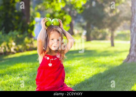 Funny bambina con mele verdi in estate park Foto Stock