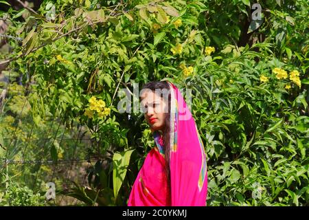 Ritratto di una bella giovane ragazza in piedi nel giardino verde e guardando la macchina fotografica Foto Stock