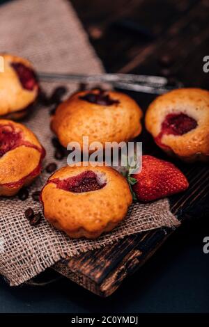 Muffin di tortine di cioccolato alla fragola su vecchio piedistallo in legno su fondo grigio di cemento. Foto Stock