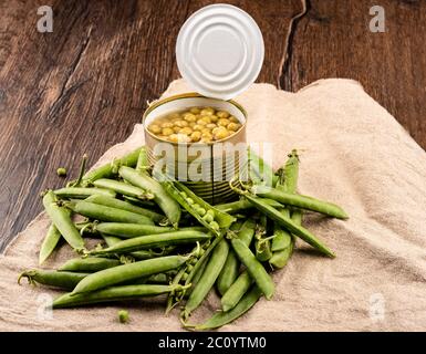 Piselli maturi in baccelli e inscatolati in un vaso. Stile rustico. Foto Stock