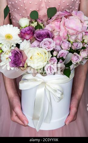 Set di fiori. Bel bouquet di fiori di lusso in una scatola rotonda bianca in mani femminili. Foto Stock