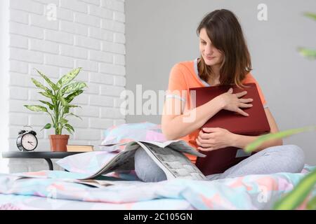 Ragazza seduta sul letto e leggendo un giornale con annunci di lavoro Foto Stock