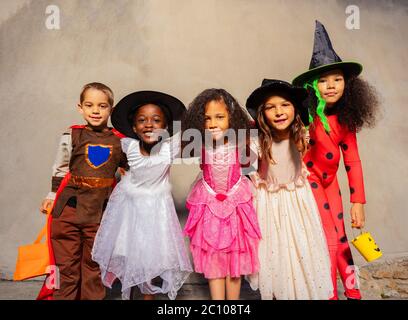 Gruppo di bambini in costumi di Halloween abbraccio in piedi insieme e sorridente guardando la macchina fotografica Foto Stock
