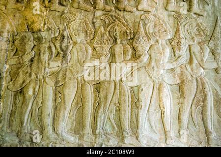 Bassorilievo scultura di una processione di dei che portano doni per Vishnu su un muro nell'angolo nord-ovest del tempio di Angkor Wat che mostra scene della Ra Foto Stock