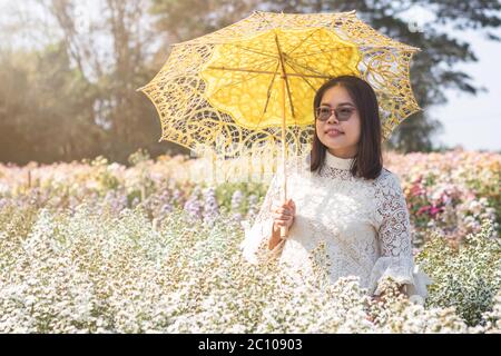 Ritratto di una donna asiatica con ombrello in un bel giardino di fiori di taglierina Bianco. Foto Stock
